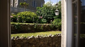 Un mur de pierre et un jardin parsemé de fleurs roses.