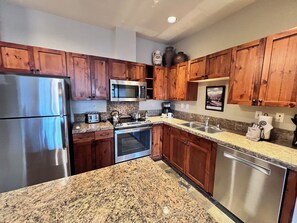 A kitchen with wooden cabinets, stainless steel appliances, granite countertops, and a built-in oven.