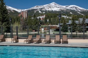 A pool area with lounge chairs and a view of snow-capped mountains.