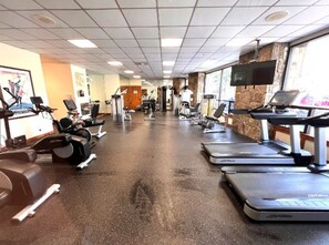 Une salle de sport équipée de tapis de course, de vélos elliptiques et de matériel de musculation.