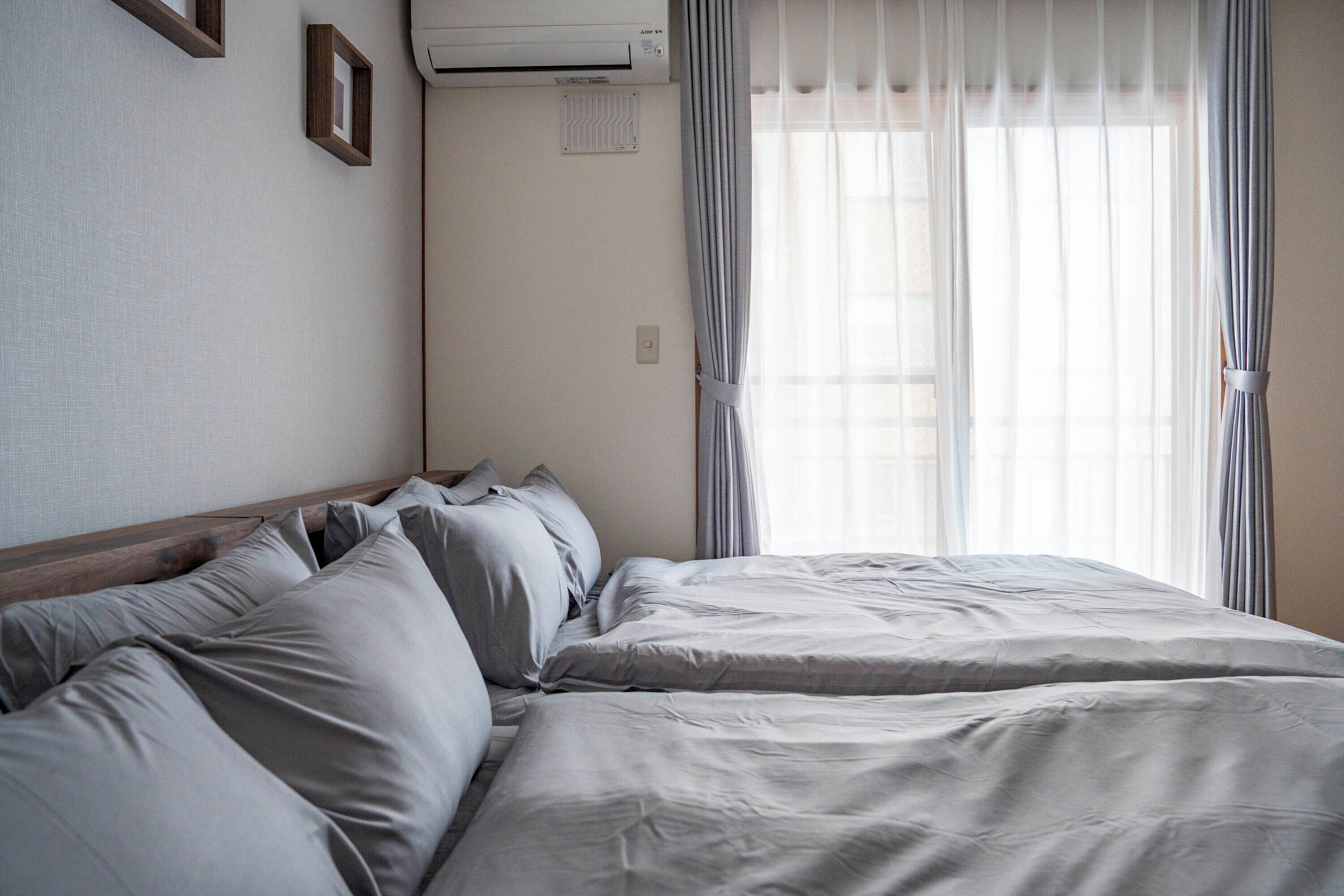 Een hotelkamer met een groot bed, een wandairco en dunne gordijnen.