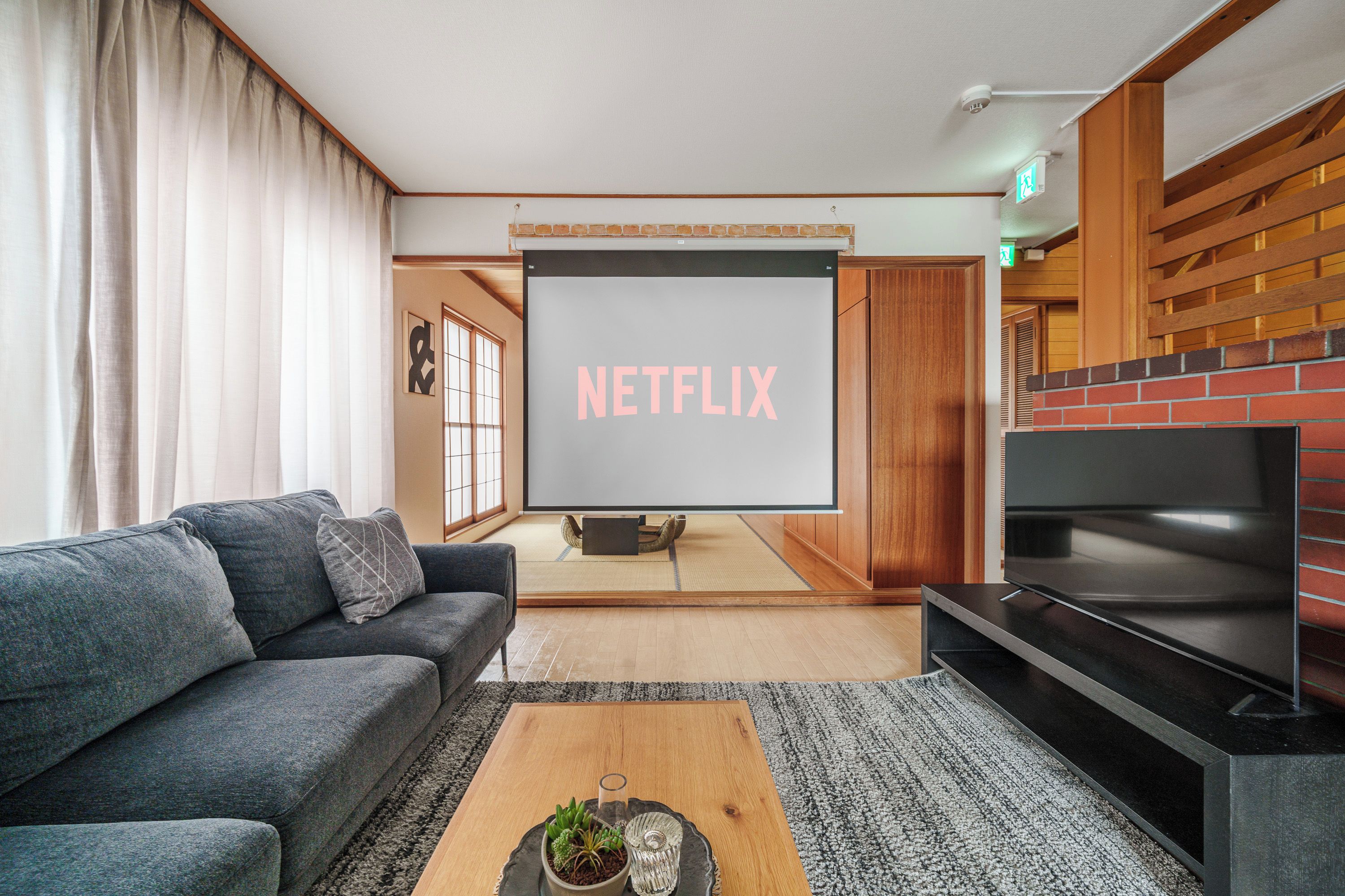 A living room with a sofa, a coffee table with a plant, a fireplace, and a TV screen displaying 'NETFLIX'.