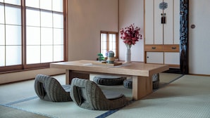 Een traditionele Japanse kamer met tatami vloerbedekking, een lage houten tafel en een lage houten kast met schuifdeuren.