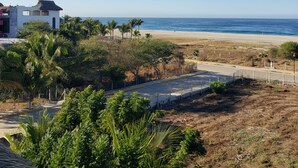 A coastal view with a beach, palm trees, and a building with a thatched roof. - BeachfrontGuestHouse (5 Studios) (Puerto Escondido)
