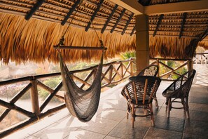 A covered outdoor seating area with woven chairs and a hanging hammock.