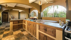 A spacious kitchen with a large island, wooden cabinets, and a gas stove. - BeachfrontGuestHouse (5 Studios) (Puerto Escondido)