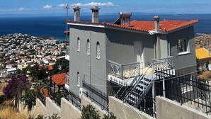 Ein Gebäude mit rotem Ziegeldach, mehreren Schornsteinen und einer Treppe, die zu einer oberen Ebene führt.