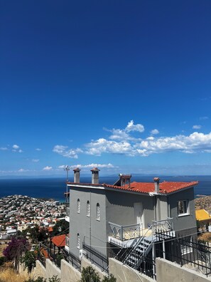 A building with a red-tiled roof, multiple chimneys, and a staircase leading to an upper level. - Panorama  Escape  Villa (Saronida)