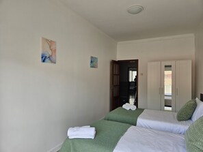 Et hotelværelse med to senge, et garderobeskab og et lille billede på væggen.