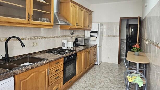 Eine Küche mit Holdekor, einer Edelstahl-Dunstabzugshaube, einer Mikrowelle, einem Toaster und einem Kühlschrank.
