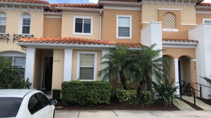 A two-story residential building with a beige facade, white trim, and a tiled roof. - Charming 3-bedroom chalet with WiFi and AC in Kissimmee (Kissimmee)