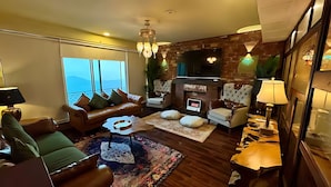 Una sala de estar moderna con un sofá de cuero, un sillón blanco, una mesa de centro y una chimenea.
