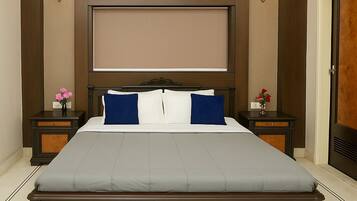 A large bed with a headboard, two bedside tables with lamps, an air conditioning unit above the headboard, and a wooden door on the right.