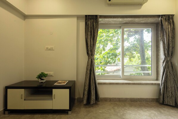 A room with a window, a small table with a plant, and a cabinet.