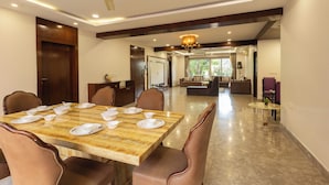 A dining area with a marble table set for six, surrounded by leather chairs. - Victoria Apartment by Jadecaps (Kolkata)