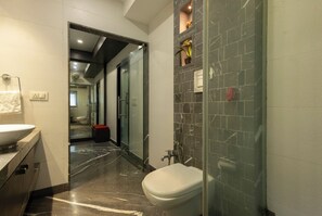 A modern bathroom with a glass shower enclosure, a white toilet, and a marble floor. - Victoria Apartment by Jadecaps (Kolkata)