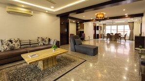 A spacious living area with a sofa, a coffee table, and a dining table. - Victoria Apartment by Jadecaps (Kolkata)