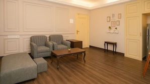 A room with a sofa set, a wooden coffee table, a small side table, and a cabinet. - Vivanta Apartment by Jadecaps (Kolkata)