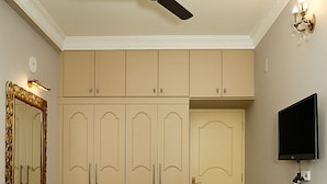A room with a ceiling fan, wardrobe, TV, and a bench. - Vivanta Apartment by Jadecaps (Kolkata)
