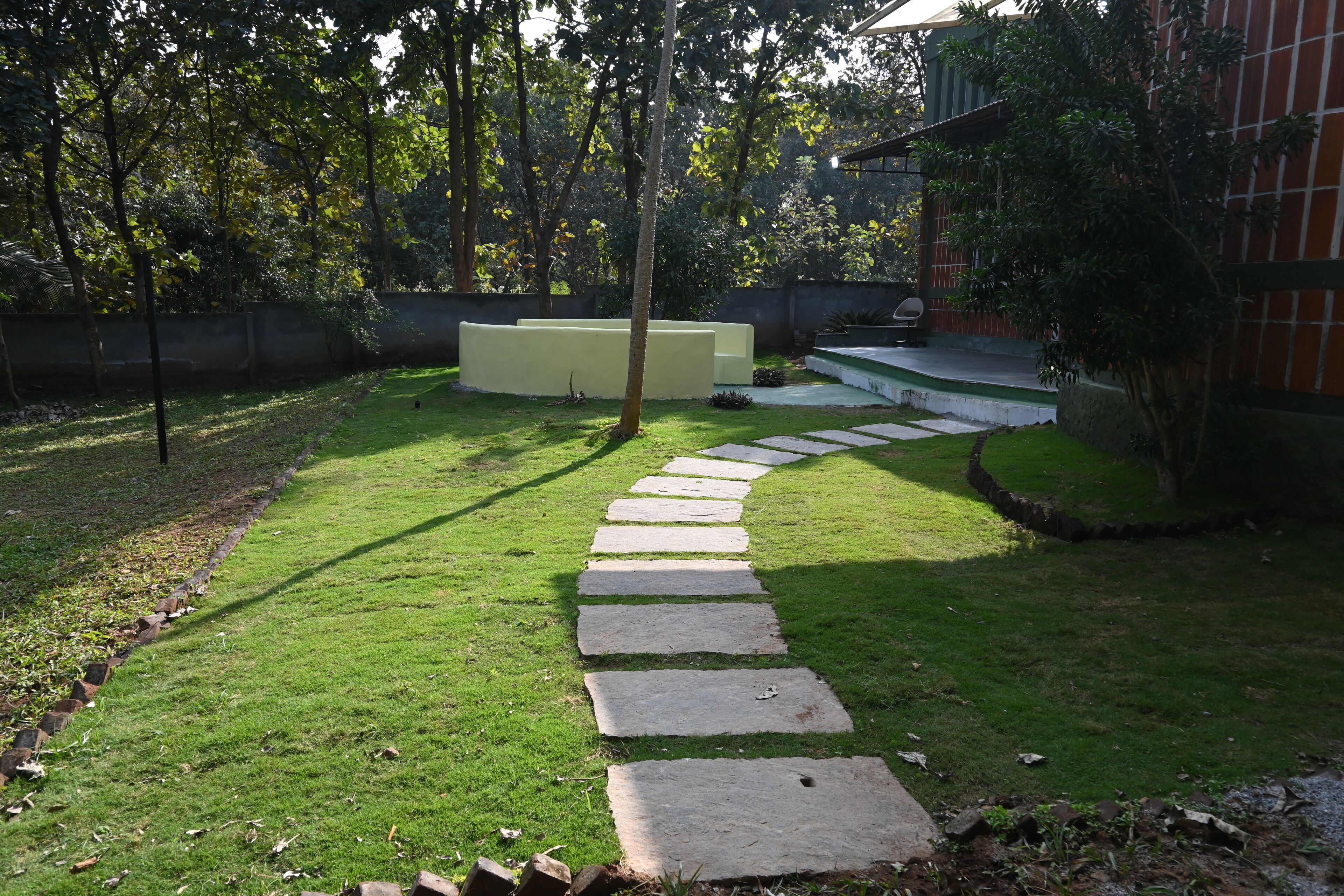 A stone pathway leading to a building with a green lawn and trees.