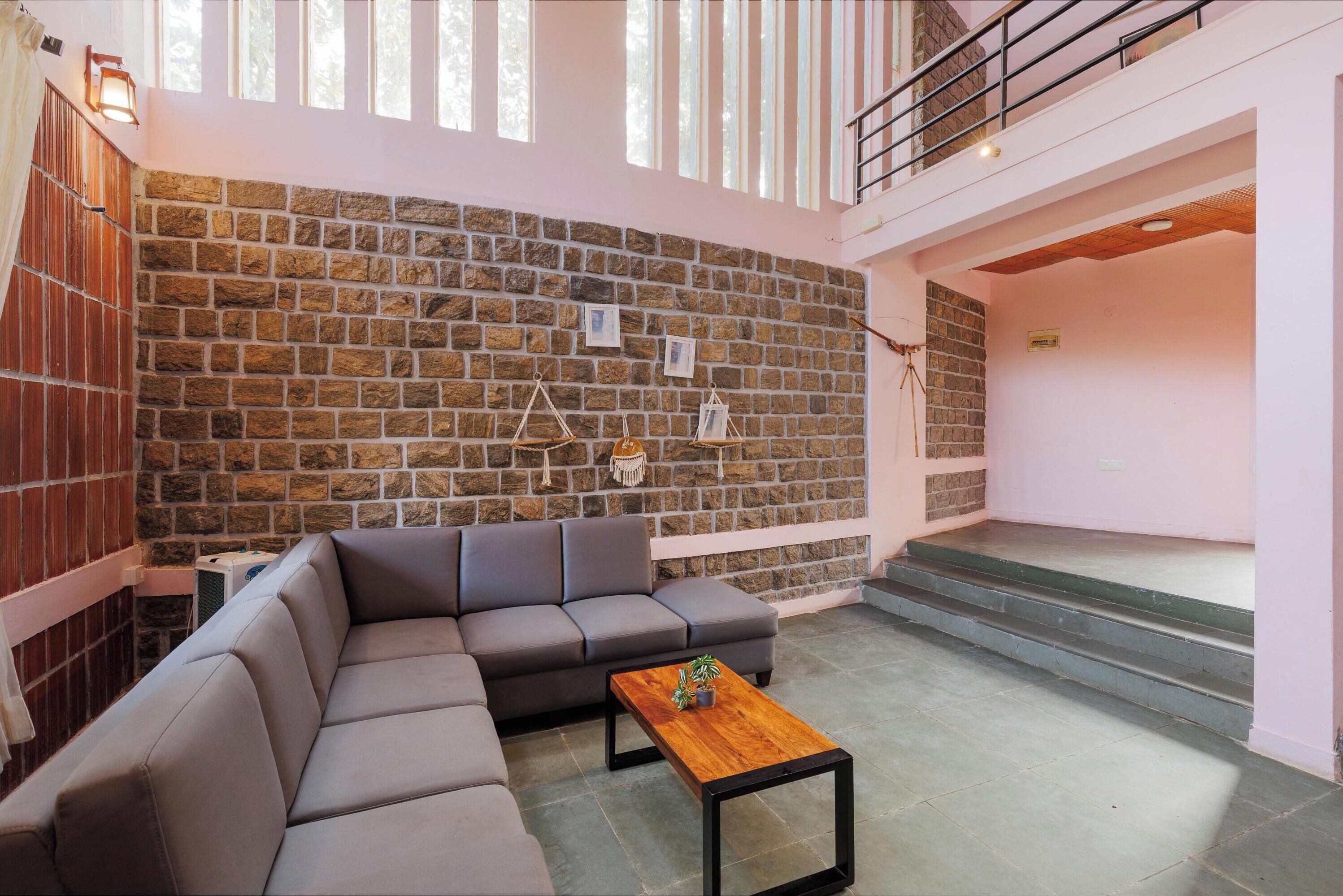 A modern living room with a stone wall, a grey sectional sofa, and a wooden coffee table.