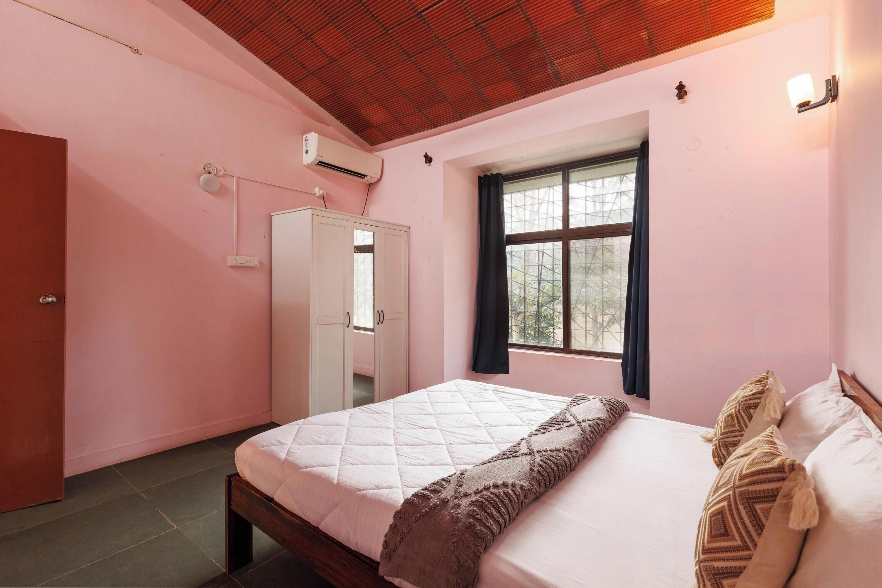 Une chambre à coucher comprenant un lit, une armoire, une fenêtre et un appareil de climatisation.