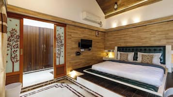 A bedroom with a large bed, wooden paneling, a flat-screen TV, and a sliding door with decorative glass panels.