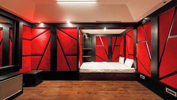 A modern bedroom with a bed, a small seating area, and a wooden floor.