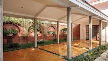 Un espacio al aire libre cubierto con suelo pulido, columnas y paredes de ladrillo con plantas.