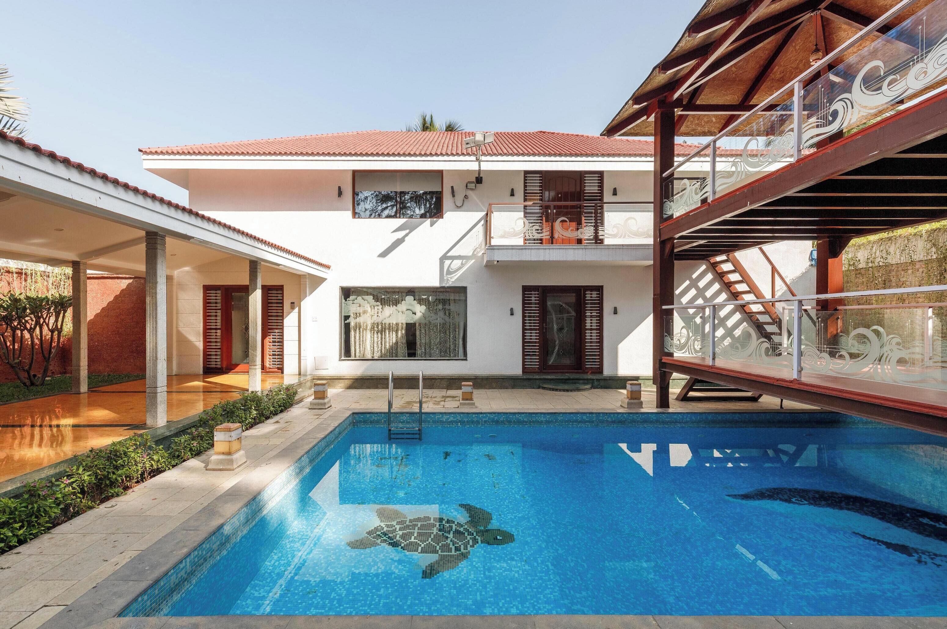 A two-story building with a swimming pool featuring a turtle mosaic.