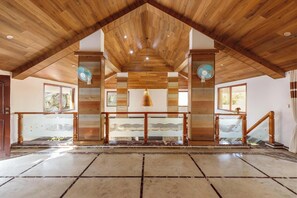 A spacious interior with a high wooden ceiling, a central staircase, and a patterned floor. - Ananta Vilas by Stayjade (Bengaluru)