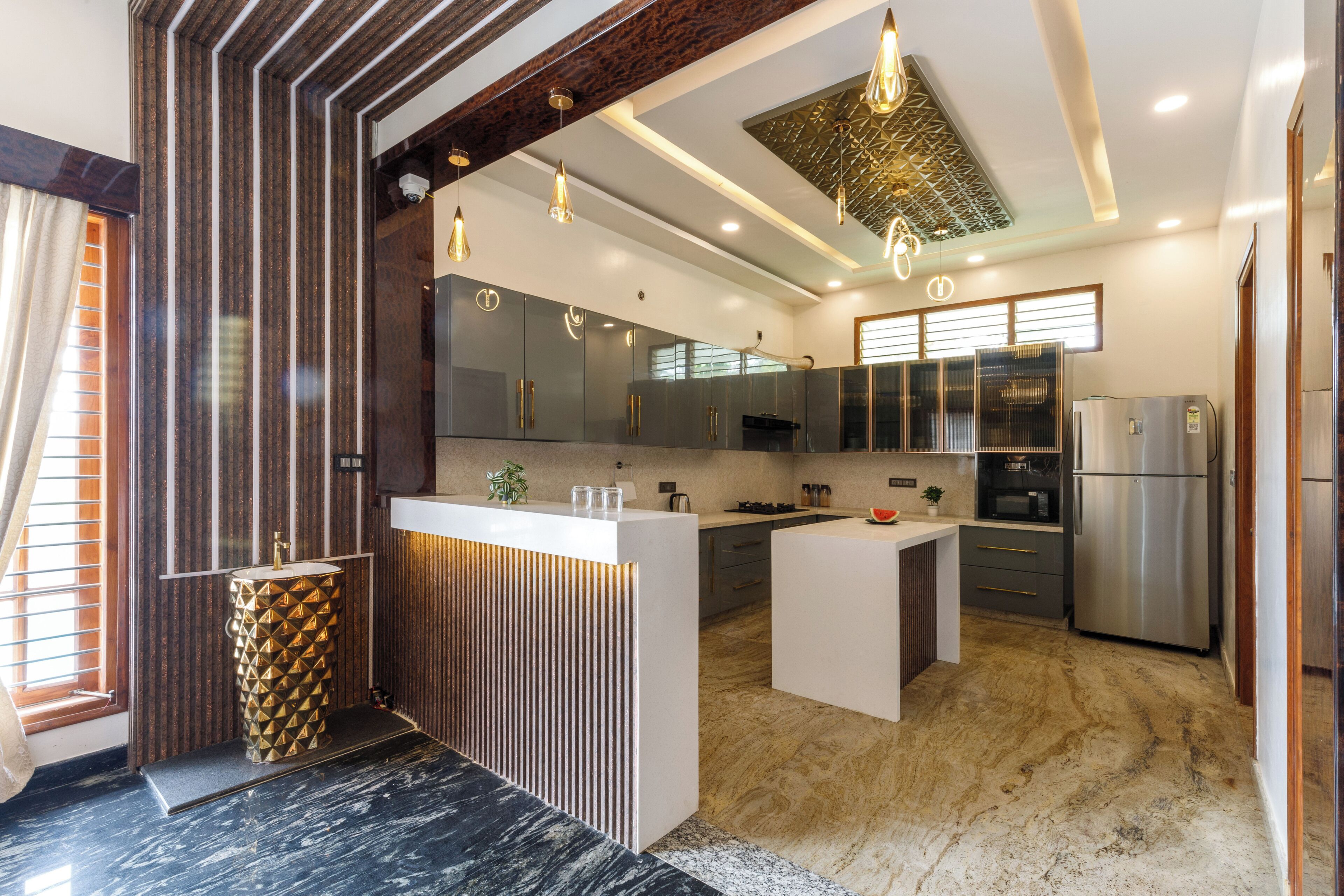 Et moderne køkken med en central ø, rustfrie apparater og et mønstret backsplash.