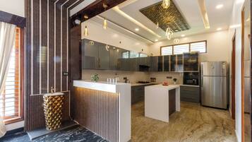 Et moderne køkken med en central ø, rustfrie apparater og et mønstret backsplash.
