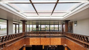 Un vaste atrium doté d’un haut plafond, de grandes fenêtres et d’un balcon agrémenté de balustrades décoratives.