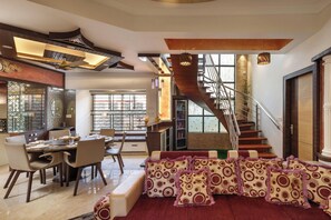 A modern interior with a dining area, a staircase, and a living room with patterned cushions. - Serenity Villa by Red Olive (Bengaluru)