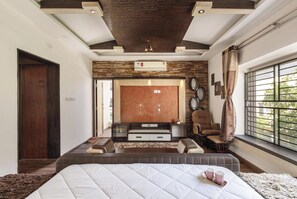 A modern bedroom with a large bed, a TV, and a seating area. - Serenity Villa by Red Olive (Bengaluru)