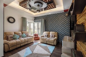 A living room with two beige sofas, a patterned rug, and a ceiling with decorative lighting. - Serenity Villa by Red Olive (Bengaluru)