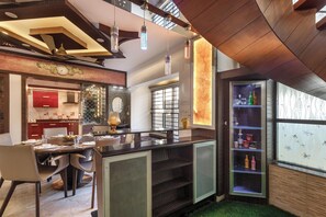 A modern kitchen with a dining area, featuring a central island, pendant lighting, and a view of the city through large windows. - Serenity Villa by Red Olive (Bengaluru)