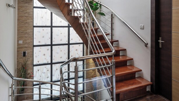 A modern staircase with wooden steps and metal railings, leading to a landing with a dark wooden door. - Serenity Villa by Red Olive (Bengaluru)