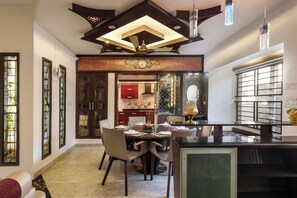 A modern kitchen with a dining area, featuring a central island, pendant lighting, and a decorative ceiling design. - Serenity Villa by Red Olive (Bengaluru)