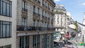 A street view with historic buildings, a modern glass-fronted building, and a busy urban environment. - Merveil Luxury Suites AboukirI-II-III-IV (Paris)