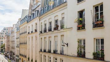 A row of classic European-style buildings with uniform facades, large windows, and balconies with potted plants.
