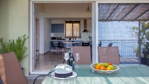 A dining area with a table, chairs, a hat, a wine bottle, and a fruit basket. - villa Marina kalamiktsi lefkada (Kalamitsi)