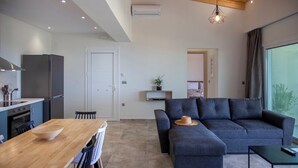 A modern kitchen with a dining area, a grey sofa, and a large window. - villa Marina kalamiktsi lefkada (Kalamitsi)