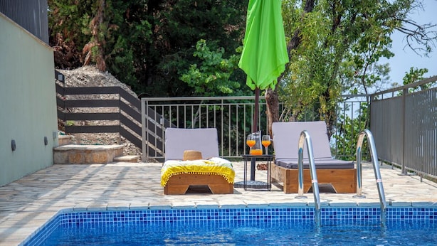 A swimming pool with lounge chairs and a table with drinks, surrounded by a stone deck and a metal fence. - villa Marina kalamiktsi lefkada (Kalamitsi)