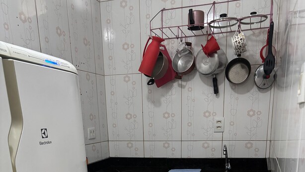 Una cocina compacta con un refrigerador blanco, una estufa a gas, un lavamanos y armarios de madera.