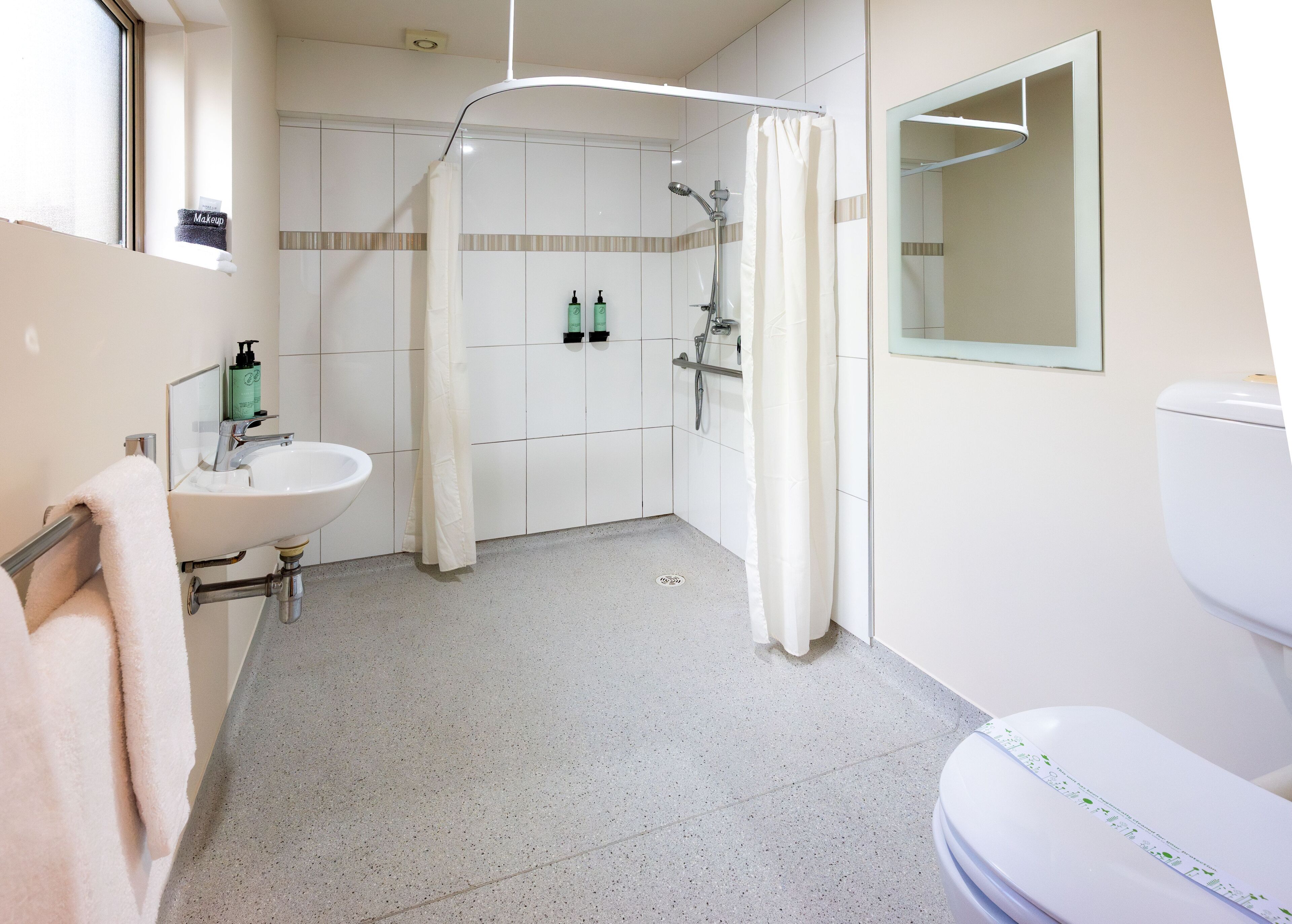 Un baño con lavabo, inodoro, ducha y un perchero para toallas.