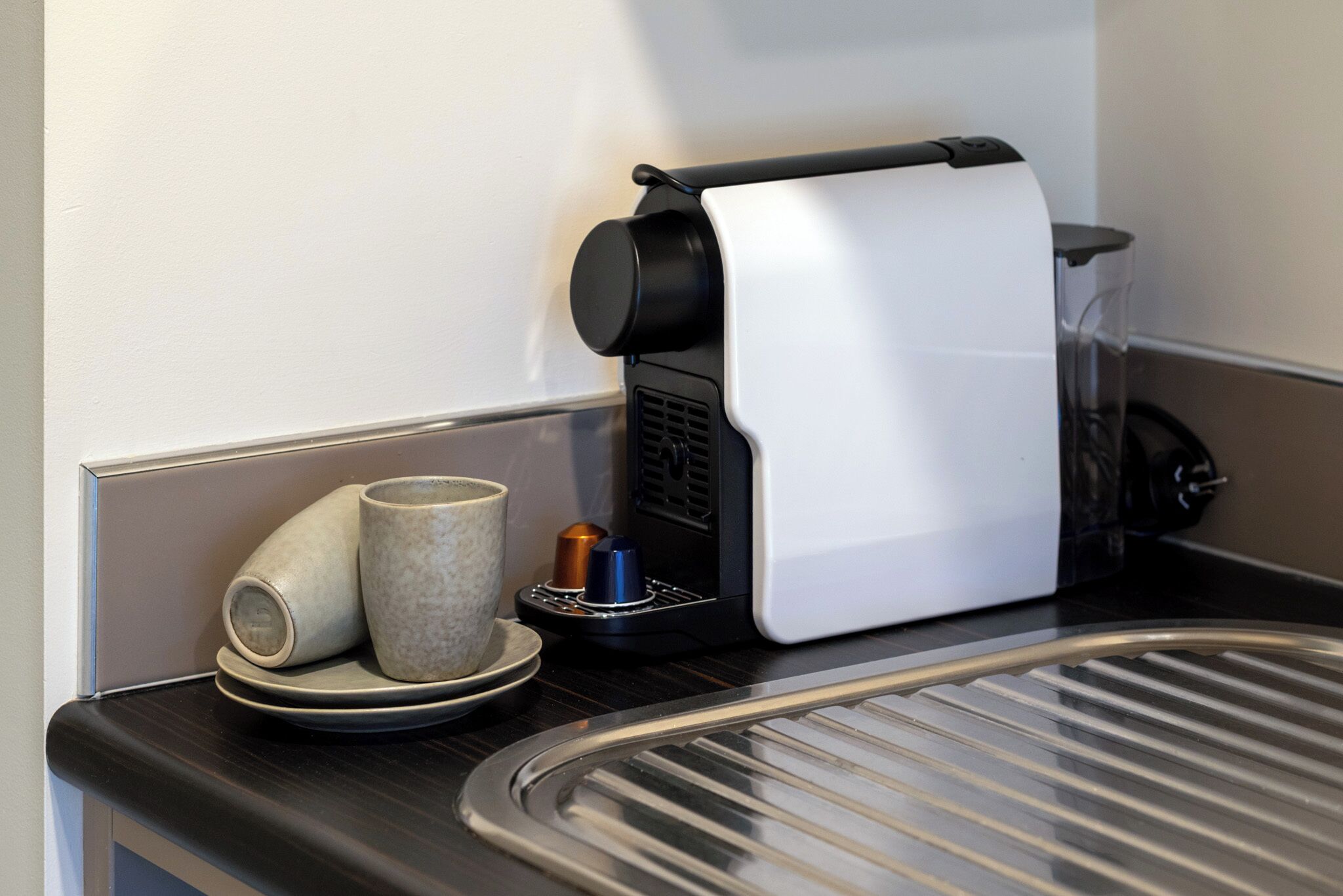 A coffee machine with a drip tray, a mug, and a plate on a countertop.