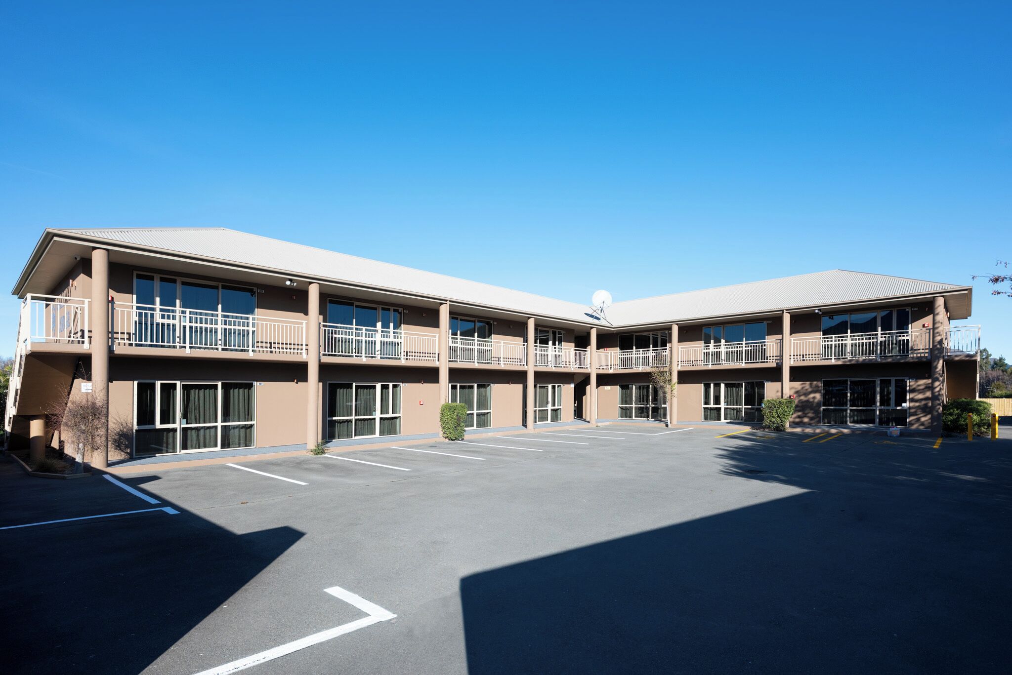 A multi-story hotel with a flat roof, large windows, and a parking lot.