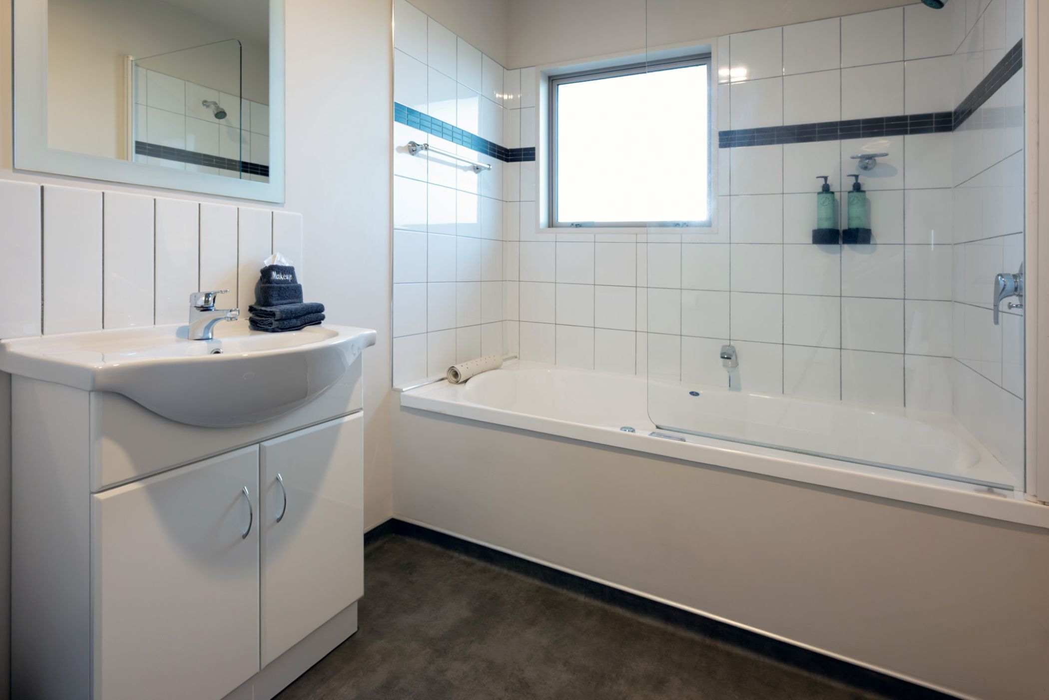 A modern bathroom with a white sink, vanity, and bathtub.